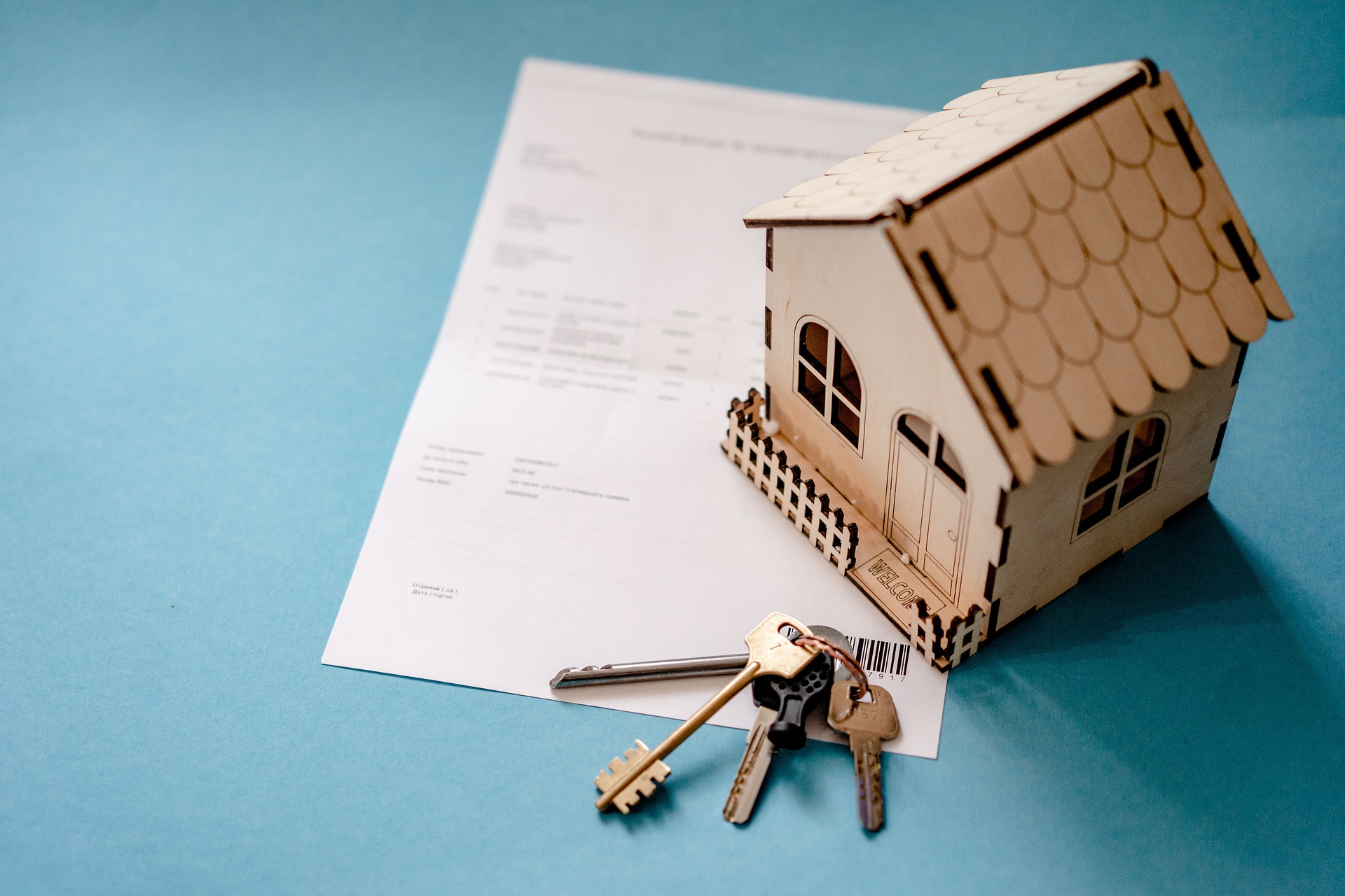 Header image for blog titled: Understanding conveyancing searches. Showing an image of a model house made out of wood with a set of keys and legal paperwork next to it.